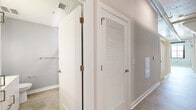 Located at 2400 Grayland Ave in Richmond, VA, this two-bedroom, one-bathroom loft delivers a compelling industrial aesthetic across a single floor. Polished concrete floors run throughout, complementing the exposed ductwork, piping, and wood-paneled ceilings that lend an authentic loft character to the space. The open-plan living and kitchen area is anchored by a well-appointed kitchen featuring stainless steel appliances—including a refrigerator, range, dishwasher, and microwave—alongside a mix of warm wood and white cabinetry with a subway tile backsplash. Track lighting illuminates the entire area. The primary bedroom is a standout, boasting painted brick walls, large black-framed windows that flood the room with natural light and offer open views of the surrounding Richmond neighborhood, and a sliding barn door. The second bedroom provides a quieter, neutral space with warm wall tones. The bathroom is sleek and modern, finished with a white vanity, a vessel-style sink, illuminated LED mirror, and a tall linen tower cabinet for added storage. A dedicated laundry room houses a stacked front-loading washer and dryer. A central hallway with louvered doors connects the rooms efficiently, completing this well-designed urban retreat.