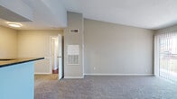 Located at 8380 El Mundo St in Houston, TX, this one-bedroom, two-bathroom unit offers a well-designed single-floor layout. The living room is immediately welcoming, featuring vaulted ceilings that create a sense of openness and volume beyond the unit's footprint, soft carpeting, and a sliding glass door that opens to a private balcony with outdoor views. The adjacent kitchen is efficiently designed with white cabinetry, dark granite countertops, a tile backsplash, and stainless steel appliances including a refrigerator, microwave, and range. A breakfast bar with a built-in sink connects the kitchen to the living area, ideal for casual dining or entertaining. The spacious primary bedroom includes a ceiling fan, plush carpeting, a sliding glass door for additional natural light and balcony access, and leads into a dedicated walk-in closet outfitted with wire shelving and basket storage systems. Both bathrooms are finished with white cabinetry, dark granite vanity tops, and clean white tile. One bathroom features a full tub-shower combination. Rich hardwood-style flooring accents the bathroom areas, providing contrast to the soft carpeting throughout the rest of the unit.