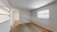 Located at 1716 NW Third Ave in Gainesville, FL, this one-bedroom, one-bathroom unit offers a practical and efficiently organized single-floor layout. The living area and bedroom feature neutral-toned wall-to-wall carpeting, creating a warm and quiet atmosphere throughout. The bedroom is a comfortable size, fitted with a ceiling fan and light fixture, a window with vertical blinds for natural light and privacy, and access to closet storage. A wall-mounted air conditioning unit provides climate control. The kitchen is equipped with white cabinetry, granite-style laminate countertops, a white coil-burner electric range with overhead ventilation hood, and ample cabinet storage above and below the counter. The bathroom showcases a retro aesthetic with distinctive terracotta hexagonal floor tiles, pink ceramic wall tiles accented by dark tile borders, a pedestal-style wall-mounted sink, a mirrored medicine cabinet, and a tub-shower combination. Two closets provide convenient additional storage throughout the unit. Windows dressed with vertical blinds are present in multiple rooms, allowing natural light to filter in while maintaining privacy. The space offers a straightforward, functional layout well-suited for everyday living.