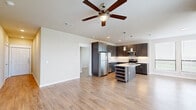 Located at 15915 Kingfield Dr in Houston, TX, this well-appointed single-story home offers three bedrooms and three bathrooms across a thoughtfully designed floor plan. The open-concept living and kitchen area serves as the heart of the home, featuring light hardwood-style flooring, a ceiling fan, and recessed lighting. The kitchen is outfitted with dark wood cabinetry, granite countertops, a white subway tile backsplash, stainless steel appliances including a refrigerator, electric range, and microwave, as well as a central island with a built-in wine rack and pendant lighting above. Large windows in the living area flood the space with natural light and offer outdoor views. The bedrooms are bright and comfortable, each with hardwood-style flooring and ceiling fans. The primary bedroom is generously sized, while additional bedrooms feature large windows with outdoor views and ample closet space. The bathrooms are finished with dark wood vanities, granite countertops, tile surround tub-shower combinations, and brushed nickel fixtures. A hallway connects the rooms efficiently, and two closets provide additional storage throughout the home.