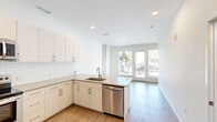 Located at 66 S Van Gordon St in Lakewood, Colorado, this modern two-story residence offers a thoughtfully designed layout across two floors. The main level features an open-concept kitchen and living area bathed in natural light from large floor-to-ceiling windows and glass doors that open to outdoor views. The kitchen is outfitted with crisp white cabinetry, a classic subway tile backsplash, quartz countertops, and a full suite of stainless steel appliances, including a refrigerator, electric range, microwave, and dishwasher. Light wood-tone flooring flows seamlessly throughout, enhancing the bright, contemporary aesthetic. A convenient half bathroom is also located on the main level. Upstairs, the generously sized primary bedroom features an expansive wall of windows with a ceiling fan, providing excellent natural light and outdoor views. A closet with built-in shelving offers practical storage. The upper floor also includes a well-appointed full bathroom with a dual-sink vanity, taupe quartz countertops, and a white subway tile shower. A stacked in-unit washer and dryer provide added convenience. Clean white walls, recessed lighting, and a consistent modern design language create a cohesive, move-in-ready living environment throughout the home.