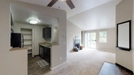 This single-floor residence offers a thoughtfully designed layout with a blend of comfort and functionality throughout. The living room serves as the heart of the home, showcasing dramatic vaulted ceilings, a ceiling fan, and a tile-surround fireplace flanked by built-in shelving. Sliding glass doors lead to a private balcony, flooding the space with natural light and providing pleasant views of surrounding greenery. Plush wall-to-wall carpeting runs throughout the living and bedroom areas, contributing to a warm and inviting ambiance.

The kitchen is designed for efficiency, featuring dark cabinetry, laminate countertops, wood-look flooring, and a full suite of appliances including a refrigerator, electric range, and microwave. A dedicated pantry closet offers additional storage, while a pass-through window connects the kitchen to the main living area.

The bedrooms are generously sized and well-lit, each offering large windows with views of mature trees and ample closet space. The bathroom continues the dark cabinetry theme with a wide vanity, stone-tone countertop, framed mirror, and wood-look flooring. The neutral color palette and clean finishes throughout create a cohesive, move-in-ready environment.