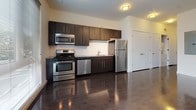 Located at 1227 Chapel Novella in New Haven, CT, this single-floor unit offers a clean, contemporary design with a well-appointed open-concept layout. Dark hardwood flooring runs throughout the main living areas, reflecting light and adding a polished aesthetic that contrasts effectively with the bright white walls.

The kitchen is a standout feature, outfitted with dark espresso cabinetry extending to the ceiling, granite countertops, and a full suite of stainless steel appliances including a gas range, microwave, dishwasher, and refrigerator. A tile backsplash and a large window facing the street flood the space with natural light, enhancing the kitchen's modern character.

The living area is generously proportioned, featuring track lighting overhead and a window that brings in additional natural light. Its open layout provides flexibility for various furniture arrangements.

The bathroom is finished with large-format dark tile flooring, a white tiled tub-shower combo, a toilet, and a dark vanity with a white countertop and mirror, maintaining the unit's consistent modern aesthetic throughout.