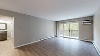 Located at 2980 Snelling Ave N in Roseville, MN, this one-bedroom, one-bathroom unit offers a well-organized single-floor layout. The living room is the centerpiece of the unit, featuring durable wood-look flooring, neutral gray walls, a baseboard heating system, and a wall-mounted air conditioning unit. Sliding glass doors open directly onto a private balcony overlooking lush, mature trees, bringing natural light and outdoor views into the space.

The galley-style kitchen is thoughtfully designed with two-tone cabinetry—white upper cabinets and dark lower cabinets—paired with granite countertops and a stainless steel sink. Stainless steel appliances, including an electric range, over-the-range microwave, and refrigerator, complete the modern kitchen setup. Light wood-look flooring and a ceiling fan add to the kitchen's clean, functional aesthetic.

The bedroom offers plush carpeting, a ceiling fan with light, a window with natural light, and a closet with a bifold door. The bathroom is fitted with wood-look flooring, a full bathtub and shower combination, a granite-topped vanity, and clean white tile surround. Two closets provide convenient storage throughout the unit.