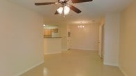 Located at 616 Highway 90 in Waveland, Mississippi, this single-story property offers a straightforward and functional layout designed for comfortable everyday living. The main living and dining area is open and spacious, filled with a bright, neutral color palette that lends a clean, airy feel to the interior. A ceiling fan with a light fixture anchors the living space, while an elegant chandelier defines the dining area, adding a touch of classic charm. Smooth, light-toned flooring runs throughout, contributing to a cohesive and easy-to-maintain interior. The kitchen is accessible directly from the main living area via a raised countertop pass-through, which also serves as a casual bar or serving surface. The kitchen features light wood cabinetry and includes a refrigerator, offering practical storage and workspace. White walls and clean baseboards throughout give the space a well-maintained appearance. Additional doorways visible from the main area suggest access to further rooms or utility spaces, rounding out a practical single-floor floor plan. The overall ambiance is bright, neutral, and move-in ready, making it a versatile space suitable for a variety of uses.