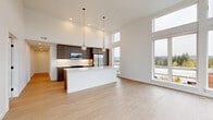 Located at 17250 NE 67th Ct in Redmond, WA, this well-appointed 3-bedroom, 3-bathroom residence offers a thoughtfully designed single-floor layout. The open-concept living and kitchen area is a standout, boasting soaring ceilings that amplify the sense of space and an abundance of natural light pouring in through expansive floor-to-ceiling windows with outdoor views of the surrounding Redmond landscape. Light-toned hardwood flooring runs throughout the main living areas, complementing the clean, modern aesthetic.

The kitchen is outfitted with rich dark wood cabinetry reaching toward the high ceilings, white quartz countertops, stainless steel appliances, and a central island with pendant lighting overhead. The living area offers generous room to relax, with large windows framing tree-lined outdoor views and access to a balcony.

Each bedroom features plush carpeting and windows that invite natural light. The primary bedroom is comfortably sized and is complemented by a well-appointed en-suite bathroom featuring a glass-enclosed shower, wood-toned vanity with white countertop, and open shelving. A dedicated laundry room with a full-size washer and dryer and wire shelving adds everyday convenience. Two hallways connect the spaces efficiently, completing this modern and functional residence.