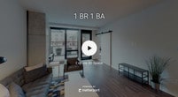 Located at 740 S 4th St in Minneapolis, this single-floor unit showcases a thoughtfully designed open-concept layout with modern finishes throughout. The kitchen serves as a functional centerpiece, featuring rich dark wood cabinetry, white subway tile backsplash, light countertops, stainless steel appliances, and a large island with pendant lighting. Track lighting and open shelving add an urban, contemporary feel, while wood-look flooring connects seamlessly to the living area.

The living room is bright and welcoming, with large floor-to-ceiling windows and a glass door that opens to a private balcony, allowing ample natural light and city views. An exposed concrete column adds an industrial architectural detail that complements the modern aesthetic. A sliding barn door provides a stylish transition between spaces.

The bedroom offers a comfortable, carpeted retreat with a ceiling fan and large windows providing natural light and outdoor views. A second bedroom with carpeting and ceiling fan offers similar comfort. The bathroom is cleanly finished with large-format tile flooring, a subway tile shower surround, and a dark wood vanity with a white countertop, maintaining the cohesive modern design found throughout the unit.