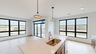 This well-designed single-floor residence offers a thoughtfully arranged layout that balances modern aesthetics with everyday functionality. The open-concept kitchen serves as the heart of the home, anchored by a generously sized island with a quartz countertop and an undermount stainless steel sink. Rich, dark wood cabinetry lines the walls and provides ample storage, while stainless steel appliances — including a range, microwave, and refrigerator — complete the space. A classic white subway tile backsplash adds a clean, timeless touch. Stylish pendant lighting hangs above the island, complementing the recessed ceiling lights throughout.

The living area flows seamlessly from the kitchen, featuring light hardwood-style flooring and large black-framed windows that frame outdoor views and flood the space with natural light. A sliding glass door leads to a private balcony, extending the living space outdoors.

The bedrooms are bright and well-proportioned, with plush carpeting, crisp white walls, and oversized black-framed windows offering sweeping exterior views. The primary bedroom connects to an en-suite bathroom with a dual-sink vanity. An additional bathroom features a full tub-shower combination with brushed nickel fixtures and hardwood-style flooring, maintaining the home's clean, contemporary style throughout.