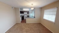 Located at 816 Kinwest Pkwy in Irving, Texas, this single-floor unit offers a functional and straightforward layout designed for comfortable everyday living. The living area is a notable highlight, featuring vaulted ceilings that lend a sense of openness, neutral-toned carpet flooring, and a tile-surround fireplace that serves as a central focal point. Natural light enters through blinded windows, contributing to a bright and inviting atmosphere.

The kitchen is open to the living and dining area and features a peninsula with granite-style countertops, providing additional workspace and a casual dining option. Dark espresso cabinetry contrasts with white appliances, including a refrigerator, electric range, and over-the-range microwave. Wood-style flooring runs throughout the kitchen, adding warmth and easy maintenance.

Bedrooms are carpeted and offer generous closet storage, including a sliding-door closet with a full hanging rod. The bathrooms are finished with dark wood vanities, granite-style countertops, undermount sinks, and large mirrors with lighted fixtures. One bathroom includes a tub-shower combination, while the other provides additional vanity space. Textured ceilings are consistent throughout the unit.