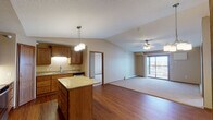 Located at 444 Victory Ave S in Sartell, Minnesota, this single-floor unit offers a well-designed open-concept layout that seamlessly connects the kitchen, dining, and living areas. The kitchen is a standout feature, equipped with rich wood cabinetry, granite countertops, a central island with pendant lighting overhead, and a full suite of stainless steel appliances including a side-by-side refrigerator, range with microwave, and dishwasher. A stacked washer and dryer unit is conveniently tucked into a dedicated closet just off the kitchen, alongside a pantry for additional storage.

The living area transitions from warm hardwood flooring to plush carpet and is brightened by a ceiling fan with light fixture and a sliding glass door that opens to a private balcony, offering outdoor views. Multiple bedrooms feature soft carpet, ceiling fans, natural light from windows with blinds, and baseboard heating. The bathrooms are finished with wide vanity countertops, large mirrors, and a combination tub and shower. Warm neutral tones, wood trim accents, and consistent finishes throughout lend the space a cohesive and comfortable atmosphere well-suited for everyday living.