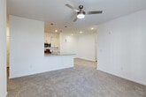 This well-designed single-story home offers a comfortable and functional layout across three bedrooms, one bathroom, and a dedicated laundry room. The open-concept living and kitchen area serves as the heart of the home, featuring plush neutral carpeting in the living space and wood-look tile flooring in the kitchen. A ceiling fan with integrated lighting anchors the living room, which is bathed in natural light from large French doors that open to the outdoors. The kitchen is thoughtfully appointed with crisp white shaker cabinetry, granite-look countertops, a subway tile backsplash, and a full suite of stainless steel appliances including a refrigerator, range, microwave, and dishwasher. A peninsula with a sink and additional seating space connects the kitchen to the living area, while pendant lighting adds a modern touch overhead. Each bedroom features soft carpeting, ceiling fans, and ample natural light from windows with blinds. The generously sized primary bedroom includes access to a walk-in closet outfitted with wire shelving and hanging rods for efficient organization. Additional closets throughout provide plentiful storage. The dedicated laundry room includes washer and dryer hookups, wire shelving, and wood-look flooring, rounding out this clean, move-in-ready home.