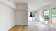 Located at 856 Nobel Dr in Santa Cruz, CA, this three-story property offers a well-organized layout spread across multiple levels, beginning with an attached two-car garage on the ground floor. The garage features a concrete floor, an automatic door opener, and fluorescent overhead lighting, providing generous vehicle and storage space.

The main living areas are finished with light-toned hardwood flooring throughout, lending a warm, cohesive aesthetic. The open living area receives abundant natural light through large sliding glass doors that open to a balcony overlooking mature greenery, complemented by a pendant light fixture above the dining area. Built-in shelving flanks an interior doorway, adding functional storage and architectural character to the space.

The kitchen is equipped with white cabinetry, light quartz-style countertops, stainless steel appliances including a gas range and microwave, and a deep single-basin sink beneath a window. Bedrooms are bright and airy, each featuring hardwood floors and windows framing views of surrounding trees.

Two bathrooms serve the home: one with a tiled tub-shower combination with sliding glass doors, and another with a standing glass-enclosed shower. A stacked in-unit washer and dryer is conveniently tucked into a dedicated utility closet, completing the home's practical offerings.