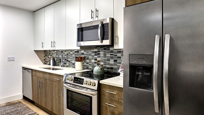 Cocina de apartamento con electrodomésticos de acero inoxidable y encimeras de cuarzo. - Griffis West Palm