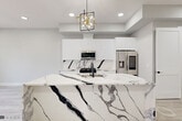 Located at 187 Culver Avenue in Jersey City, NJ, this thoughtfully designed single-floor home offers three bedrooms and two full bathrooms with a cohesive modern aesthetic. The open-concept kitchen serves as the centerpiece of the home, showcasing a dramatic marble waterfall island with bold black and grey veining, high-gloss white cabinetry extending to the ceiling, a matching marble backsplash, and stainless steel appliances including a gas range and French door refrigerator. A geometric gold-accented pendant light adds a refined finishing touch overhead. Both bathrooms are finished with floor-to-ceiling marble-look tile in a crisp white and grey palette, complemented by floating vanities with white countertops, matte black fixtures and hardware, dark slate-toned floor tiles, and mirrored medicine cabinets. The three bedrooms feature light wood-look flooring, neutral grey-toned walls, clean white trim, and panel-style doors with matte black hardware. At least one bedroom includes a well-organized built-in closet with dedicated shelving and hanging rods. Recessed lighting throughout ensures a bright, clean atmosphere, while the consistent use of white tones and marble-inspired surfaces creates a cohesive, contemporary feel across the entire home.