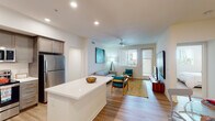 Located at 2640 Wagon Wheel Rd in Oxnard, California, this single-floor residence offers a thoughtfully designed open-concept layout that seamlessly connects the kitchen, dining area, and living spaces. The interior is finished with light wood-style flooring throughout the main areas, complemented by neutral-toned walls that create a bright, airy atmosphere.

The kitchen is well-equipped with stainless steel appliances, including a refrigerator, electric range, microwave, and dishwasher. Crisp white cabinetry with modern hardware pairs with gray countertops to deliver a clean, contemporary aesthetic. The adjacent dining area accommodates a full-sized table, flowing naturally into the spacious living room, which features a ceiling fan, recessed lighting, and a glass door leading to an outdoor patio area.

The living room offers generous space for multiple seating arrangements and benefits from natural light through large windows. The bedrooms are carpeted for comfort, each featuring windows with views of surrounding greenery. The bathroom is notably spacious, featuring wood-style flooring, a wide vanity, and grab bar accessibility. Overall, the residence presents a cohesive, modern design with a comfortable and functional single-level floor plan.