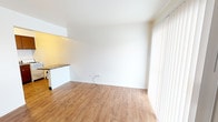 Located at 3726 Union Ave in Steger, Illinois, this single-floor unit offers a straightforward and functional layout across several distinct areas. The living space is bright and open, featuring light wood-look laminate flooring and clean white walls that create a fresh, neutral atmosphere. A large sliding glass door fitted with vertical blinds allows natural light to fill the room and provides an outdoor view.

The kitchen is positioned adjacent to the living area and is accessible through an open pass-through counter with a stone-look surface. It is equipped with dark brown cabinetry, a double-basin sink, a white gas range, and a white tile backsplash — offering a compact yet fully functional cooking space.

The bedroom features the same warm-toned hardwood-style flooring seen throughout the unit, with a sliding glass door providing additional natural light and outdoor access. Built-in closet space is available, offering practical storage. A wall-mounted air conditioning unit keeps the room climate-controlled.

The bathroom retains a classic character, highlighted by pink tile wainscoting along the lower walls. It includes a white vanity with a mirror, standard toilet, and chrome fixtures and accessories. Wood-look flooring continues into this space, tying the unit together cohesively. Overall, the space presents a clean, move-in ready environment with functional amenities throughout.