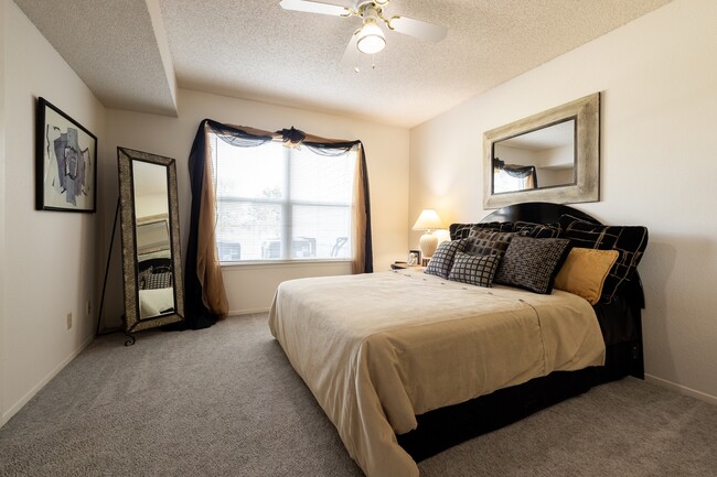 Find your sanctuary in this cozy bedroom with dark wood accents, soft bedding, and plenty of natural light. The perfect place to unwind after a long day. - The Lakes Apartments