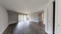 This single-floor unit offers a well-organized layout with a clean, contemporary aesthetic throughout. The open living area is anchored by dark hardwood-style flooring and neutral gray walls, creating a sleek and cohesive atmosphere. Large sliding glass doors fitted with vertical blinds allow an abundance of natural light to flow into the space while providing access to the outdoors.

The kitchen is thoughtfully designed with dark shaker-style cabinetry, light quartz countertops, and a classic subway tile backsplash. A full suite of stainless steel appliances—including a gas range, dishwasher, over-the-range microwave, and refrigerator—adds both functionality and a modern edge. A peninsula counter extends from the kitchen, offering additional prep space and a natural transition to the living area.

The bedrooms are finished with plush neutral carpeting and feature built-in closets with rod and shelf systems. Angled ceilings in one bedroom lend the room a distinctive architectural character. The bathroom includes tile flooring, a dark wood vanity, and a tub-shower combination with a detailed mosaic tile surround. A staircase with warm wood treads connects the levels of the unit.
