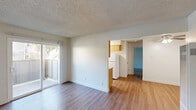 Located at 4918 N 9th St in Fresno, CA, this one-bedroom, one-bathroom residence offers a well-organized single-floor layout designed for comfortable everyday living. The living room features wood-style laminate flooring, a textured ceiling, and a wall-mounted air conditioning unit, with sliding glass doors that open directly onto a private patio, filling the space with natural light and providing easy outdoor access. The galley-style kitchen and dining area are efficiently laid out with warm honey-toned cabinetry, granite-look countertops, white appliances including a refrigerator, electric range, and microwave, plus a ceiling fan overhead. A window at the end of the kitchen brings in additional natural light. The bedroom is generously proportioned with plush carpeting, a large window overlooking the outdoors, and access to multiple closets, offering abundant storage. The bathroom features a wide vanity with granite-look countertops, warm wood cabinetry, and a large mirror. Additional highlights include a pantry, a hallway connecting the main living areas, and four closets distributed throughout the unit. The consistent wood-style flooring in the common areas and clean white walls throughout create a bright, cohesive aesthetic.