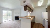 Located at 534 Hunt Ln in San Antonio, TX, this single-story unit offers a well-organized, open layout designed for comfortable everyday living. The heart of the home is the open-concept kitchen and living area, where a peninsula with granite-style countertops and dark wood cabinetry provides a natural divide between the two spaces. The kitchen is equipped with a white range, refrigerator, and a sink overlooking the living room. Overhead cabinetry with under-cabinet lighting adds both storage and functionality. The living room is carpeted and anchored by a tile-surround wood-burning fireplace with a classic white mantel, creating a cozy focal point. Sliding glass doors flood the space with natural light and offer direct access to an outdoor balcony. The bedroom is generously proportioned, featuring plush carpeting, a ceiling fan with light fixture, and an arched window that brings in additional natural light. The bathroom includes a full tub and shower combo with white tile surround, a vanity with matching countertops, and hardwood-style flooring. Throughout the unit, a consistent palette of white walls, warm cabinetry tones, and neutral flooring creates a cohesive and inviting atmosphere.