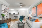This single-floor residence in Columbus, Georgia offers a thoughtfully designed layout with a warm, contemporary aesthetic throughout. The kitchen features white cabinetry, light stone countertops, black appliances, and a peninsula breakfast bar with seating — seamlessly connecting to the main living area, which is finished with wood-look flooring and neutral tones. A dedicated dining room impresses with crown molding, hardwood-style floors, a modern chandelier, and a bold abstract artwork that anchors the space with color and character. The living room continues the curated feel with soft, neutral walls, decorative crown molding, and carefully placed accent pieces. A cozy reading nook with a leather accent chair adds a functional yet stylish touch. The bedrooms offer plush carpeting, generous natural light from large windows dressed with floor-length drapes, and restful, earthy palettes. The primary bedroom features an elegantly styled headboard and warm ambient lighting. Bathrooms are finished with wood-look flooring, white vanity cabinetry, and clean tile surrounds in the shower-tub combination. A dedicated laundry closet with a full-size washer provides added convenience. The overall ambiance is cohesive, comfortable, and move-in ready.