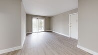 This 2-bedroom, 1-bathroom unit in the Georgetown South neighborhood of Lafayette, Indiana, presents a clean, modern interior finished with consistent light wood-style luxury vinyl plank flooring throughout. The open living room serves as the heart of the unit, featuring neutral gray-toned walls, white baseboards, and a sliding glass door that provides natural light and access to an outdoor balcony with neighborhood views. A pass-through window connects the living area directly to the kitchen, enhancing the open feel of the shared space.

The kitchen is well-appointed with white shaker-style cabinetry, marble-patterned countertops, a stainless steel refrigerator, and a dedicated hallway leading further into the unit. Both bedrooms offer comfortable proportions, neutral walls, and natural light through windows fitted with blinds. The primary bedroom includes a built-in closet with sliding doors. A central hallway connects the bedrooms to the shared bathroom, which features a white vanity with a modern brushed-nickel faucet, a large mirror, marble-style tile flooring, and clean, neutral finishes throughout. The overall ambiance is bright, cohesive, and move-in ready.