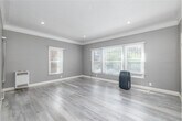 Located at 681 Shatto Pl in the heart of Los Angeles, this efficiently designed single-floor unit offers a thoughtfully arranged layout comprising a living room, kitchen, bathroom, closet, and hallway. The living room is a bright, welcoming space featuring soft gray walls, elegant crown molding, light wood-style flooring, and multiple windows dressed with white blinds that invite natural light. A wall-mounted heating unit adds a practical touch to this clean, open area. The kitchen is a standout, showcasing modern gray flat-front cabinetry, a striking marble-look tile backsplash, light quartz countertops, and a full suite of stainless steel appliances including a gas range with a stainless hood, refrigerator, and dishwasher. The hallway connects the spaces seamlessly, continuing the light wood flooring and neutral gray palette. The bathroom features elegant marble-style tile flooring, a pedestal-style vanity with a mirror, and a window for natural ventilation. A dedicated closet with barn-style sliding doors provides convenient storage. Recessed lighting, white baseboards, and consistent neutral tones throughout give the space a cohesive, modern aesthetic well-suited to urban living in Los Angeles.