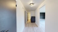 Located at 249 Lowrey Pl in Newington, CT, this thoughtfully renovated 2-bedroom, 1-bathroom home offers a clean, modern aesthetic across a single, efficiently arranged floor. Light wood-tone flooring runs throughout, creating a cohesive and bright feel in every room. The kitchen is a standout feature, showcasing two-tone cabinetry with white upper shaker cabinets and slate-blue lower cabinets, complemented by a dramatic white-and-black veined marble backsplash, quartz countertops, a matte black faucet, and a full suite of stainless steel appliances including a gas range, dishwasher, and refrigerator. Stylish flush-mount light fixtures add a modern touch overhead. The living room makes a bold statement with a full dark-painted brick accent wall and light wood flooring, creating a striking contemporary contrast. A well-lit hallway with decorative ceiling lighting connects the main living areas to both bedrooms, each featuring soft gray walls, light wood flooring, and dark-paneled sliding closet doors. The spacious primary bedroom offers a generous closet and natural light from a window overlooking the surroundings. The bathroom is elegantly finished with a marble-surround tub-shower combination, a wood-toned vanity with white countertop, and matte black fixtures, rounding out this move-in-ready home.