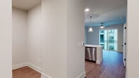 This single-floor residence offers a well-designed open-concept layout with a seamless flow between the kitchen and living areas. The kitchen is a standout feature, equipped with a full suite of stainless steel appliances, including a refrigerator, electric range, over-the-range microwave, and dishwasher. Gray shaker-style cabinetry with matte black hardware lines the walls, complemented by a gray tile backsplash and light quartz countertops. A peninsula with an integrated sink extends into the living space, topped with pendant lights that add a contemporary touch. Wood-look flooring runs throughout the main living areas, providing a warm, cohesive aesthetic.

The bedroom is finished with plush carpet and features multiple large windows dressed with white horizontal blinds, allowing ample natural light and views of the surrounding urban environment. A ceiling fan is present in the living area, contributing to comfort year-round.

The bathroom is outfitted with a tub and shower combination, fully tiled in classic white subway tile with contrasting matte black fixtures, adding a modern yet timeless design element. The overall color palette throughout the space is neutral and clean, creating a bright, move-in-ready environment.