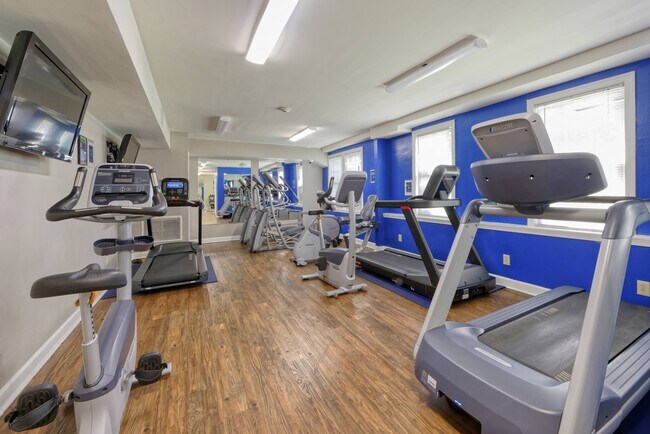 Un gimnasio con equipos cardiovasculares y cintas de correr. - Park Crest Apartments