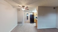 Located at 9401 Hurstbourne Crossing Dr in Louisville, Kentucky, this single-floor unit offers a practical and well-organized layout suited for comfortable everyday living. The open living area is finished with neutral-toned carpet and features a ceiling fan with integrated lighting, along with a textured ceiling that adds subtle character. Visible HVAC vents throughout ensure year-round climate control. The living space flows directly toward the kitchen and a hallway leading to the private rooms.

The galley-style kitchen is outfitted with warm oak cabinetry offering generous upper and lower storage, dark granite-style countertops, a stainless steel sink, and black appliances including a refrigerator and an electric range with hood ventilation. Wood-look flooring runs through the kitchen, providing a durable and easy-to-maintain surface. An electrical panel is conveniently accessible within the kitchen.

The bedrooms are carpeted and finished with neutral walls, each featuring windows with blinds that allow for natural light and outdoor views of surrounding greenery. The full bathroom includes wood-look flooring, a single-sink vanity with oak cabinetry, a toilet, and a tub-shower combination with a clean, white surround. The overall design is functional and move-in ready, making it a practical living space in the Hurstbourne Crossing community.