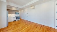 This 530 square foot apartment in Brooklyn offers a contemporary living space with two bedrooms and one bathroom. The open-concept design maximizes the use of space, combining the kitchen and living area. The kitchen boasts modern white cabinetry, stainless steel appliances, and a marble-like backsplash, creating a sleek and functional cooking space.

Large windows dominate the living area and bedrooms, flooding the space with natural light and providing panoramic views of the Brooklyn skyline. The warm-toned hardwood flooring throughout adds a touch of warmth to the crisp white walls.

The primary bedroom, measuring 100 square feet, offers ample space and features the same expansive windows. The bathroom is efficiently designed with a modern vanity, large mirror, and clean lines. Air conditioning units in the rooms ensure year-round comfort.

Despite its compact size, the apartment makes excellent use of vertical space with high ceilings and overhead storage in the kitchen. The layout is thoughtfully planned to maximize functionality and create a sense of spaciousness. Located at 2715 Fulton St, this apartment combines urban living with modern amenities in a prime Brooklyn location.