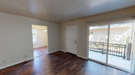 Located at 1420 F St in Davis, CA, this single-floor apartment offers a well-designed layout with a blend of practical finishes and inviting living spaces. The main living area features rich, dark hardwood-style flooring that extends throughout, complemented by neutral-toned walls that create a clean, open atmosphere. A sliding glass door leads to a private balcony, allowing natural light to flow in and providing an outdoor retreat. An arched passageway connects the living area to an adjacent room, enhancing the sense of flow throughout the unit. The kitchen is efficiently laid out in a U-shape, featuring light wood cabinetry, laminate countertops, a built-in electric range, and a full-size refrigerator, all set atop the same warm hardwood-style flooring. The bedrooms are carpeted and bright, each featuring large sliding windows that invite abundant natural light and views of surrounding greenery. One bedroom includes a closet, adding practical storage. The unit includes two bathrooms: one featuring a full bathtub with shower, white vanity cabinetry, and hardwood-style flooring; the other offering a standalone shower stall, vanity, and additional storage cabinetry. Throughout, the space maintains a light, neutral palette that is both functional and easy to personalize.