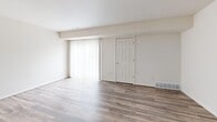 This two-story, 2-bedroom, 2-bathroom home in Okemos, Michigan offers a practical and clean layout spread across two floors. The main floor features a bright living room with wood-look laminate flooring, neutral walls, and a large sliding glass door dressed with vertical blinds that allow abundant natural light to filter in. The kitchen is designed with a pass-through counter, light gray wood-panel cabinetry, marble-style countertops, a double stainless steel sink, and a full suite of appliances including a stainless steel refrigerator, electric range, and dishwasher. The kitchen also features matching wood-look flooring, creating a cohesive feel throughout the main living areas. Upstairs, both bedrooms are carpeted in warm neutral tones and feature double-door closets, offering ample storage. The generously sized primary bedroom includes an adjacent bathroom with a wide white vanity, a large mirror with overhead lighting, and wood-look tile flooring. The second bathroom is equally well-appointed, featuring a tub-shower combination, wood-look flooring, and a window for natural ventilation. A connecting hallway links the upper-level rooms seamlessly. Overall, the home presents a clean, functional aesthetic with consistent finishes throughout.