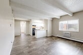 Located at 1082 S Dahlia St in Glendale, Colorado, this one-bedroom, one-bathroom unit offers a well-utilized, single-floor layout with a clean, neutral aesthetic throughout. The open-concept living and dining area flows seamlessly into the kitchen, creating a connected and functional common space. Wood-look flooring extends across the main living areas, complemented by a textured ceiling and distinctive exposed structural beams that add architectural character. A wall-mounted HVAC unit and baseboard heating provide year-round comfort, while multiple windows invite natural light and offer views of the surrounding neighborhood. The kitchen features white cabinetry, light stone-look countertops, a peninsula with additional counter space, black appliances, and a window above the sink. The bedroom is carpeted for warmth and comfort, and includes a window with neighborhood views and baseboard heating. A dedicated closet provides practical storage. The bathroom is clean and bright, with wood-look flooring, a shower-tub combination, and a small window for ventilation. Overall, the unit presents a straightforward and practical living space with consistent finishes and a neutral palette throughout.