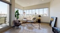 This contemporary single-floor residence showcases a thoughtfully designed layout with polished concrete floors and a neutral palette throughout. The living area is a standout, featuring a wide bank of floor-to-ceiling windows that flood the space with natural light and offer open views of the surrounding neighborhood, creating an airy, sunlit atmosphere ideal for both relaxing and entertaining.

The kitchen is outfitted with wood-toned cabinetry extending to the ceiling, stainless steel appliances including a gas range, built-in microwave, and French door refrigerator, complemented by a geometric tile backsplash and light countertops. A window above the counter brings in additional natural light.

The two bedrooms offer a calm retreat, each with dedicated closet space featuring frosted glass sliding doors and built-in shelving and hanging rods. One bedroom features polished concrete floors, while the other is finished with carpet for added comfort. Both rooms receive natural light through well-placed windows.

The two bathrooms mirror each other in style, each offering a tub-shower combination with glass sliding doors, tiled walls, built-in recessed shelving, floating vanities, and backlit mirrors, delivering a clean, modern aesthetic throughout.