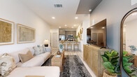 This single-floor unit offers a thoughtfully organized layout that maximizes every square foot. The open-plan living and kitchen area forms the heart of the space, where light-toned luxury vinyl plank flooring, recessed lighting, and crisp white walls create a bright, cohesive atmosphere. The kitchen is outfitted with grey shaker-style cabinetry, stainless steel appliances, a tile backsplash, and a marble-topped peninsula with bar seating—an ideal spot for casual dining or entertaining. The living area accommodates comfortable seating and benefits from natural light streaming through windows, complemented by a ceiling fan overhead.

The bedroom is a calm retreat, featuring plush carpet, multiple windows that invite natural light and outdoor views, and sufficient space for a full furniture arrangement. An adjacent closet provides dedicated storage.

The full bathroom includes a shower-tub combination with floor-to-ceiling tile surround, a vanity with dark cabinetry, and light wood-look flooring. A separate in-unit laundry area houses a full-sized washer and dryer with overhead shelving. The overall design balances practicality with a warm, contemporary aesthetic throughout.