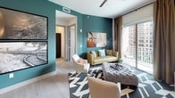 Located in the vibrant Uptown neighborhood of Dallas, this single-floor residence at 3031 Allen St showcases a thoughtfully designed interior with a bold, contemporary aesthetic. Light wood-style flooring flows throughout the main living areas, anchoring an open-concept layout that connects the kitchen, dining, and living spaces seamlessly.

The kitchen is a standout feature, outfitted with dark espresso cabinetry reaching toward the ceiling, white quartz countertops, stainless steel appliances, a built-in wine cooler, and a generously sized center island ideal for casual dining or entertaining. Pendant lighting adds a refined touch overhead.

The living area makes a striking impression with deep teal accent walls, large windows, and access to a private balcony offering urban views of the Dallas skyline. A dedicated lounge nook features music-themed décor, including framed sheet music artwork and a neon sign, creating a curated, personality-rich corner.

The bedroom is bathed in natural light from oversized windows with city views, complemented by a bold floral accent wall. The spa-inspired bathroom includes a soaking tub, glass-enclosed shower, dual-sink vanity with backlit mirrors, and direct access to a well-organized walk-in closet.