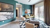 Located in the vibrant Uptown neighborhood of Dallas, this single-floor residence at 3031 Allen St showcases a thoughtfully designed interior with a bold, contemporary aesthetic. Light wood-style flooring flows throughout the main living areas, anchoring an open-concept layout that connects the kitchen, dining, and living spaces seamlessly.

The kitchen is a standout feature, outfitted with dark espresso cabinetry reaching toward the ceiling, white quartz countertops, stainless steel appliances, a built-in wine cooler, and a generously sized center island ideal for casual dining or entertaining. Pendant lighting adds a refined touch overhead.

The living area makes a striking impression with deep teal accent walls, large windows, and access to a private balcony offering urban views of the Dallas skyline. A dedicated lounge nook features music-themed décor, including framed sheet music artwork and a neon sign, creating a curated, personality-rich corner.

The bedroom is bathed in natural light from oversized windows with city views, complemented by a bold floral accent wall. The spa-inspired bathroom includes a soaking tub, glass-enclosed shower, dual-sink vanity with backlit mirrors, and direct access to a well-organized walk-in closet.