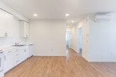 Located at 975 First St in Gilroy, CA, this single-story 2-bedroom, 1-bathroom unit offers a thoughtfully laid-out living space with a clean, modern aesthetic. Light wood-style flooring runs throughout, complementing the crisp white walls and creating a bright, cohesive feel across every room.

The open kitchen and dining area is well-appointed with full-height white cabinetry, white countertops, a full suite of white appliances including a refrigerator, electric range, microwave, and dishwasher, plus a stainless steel sink. Recessed lighting illuminates the space efficiently. Adjacent to the kitchen, the living area provides an open and flexible layout, enhanced by a wall-mounted mini-split HVAC unit for year-round comfort.

A hallway connects the living areas to the two bedrooms, both of which are generously proportioned with light-filled windows offering views of greenery outside. The primary bedroom includes a sliding-door closet, and the unit features a total of three closets for ample storage. The bathroom is finished in a clean, functional style with wood-look tile flooring, grab bars, a vanity with storage, and a toilet. The overall ambiance is fresh and move-in ready, suited for comfortable everyday living.