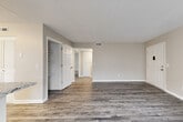 Located in Chattanooga, TN, this well-appointed single-floor unit offers a thoughtfully designed open-concept layout with modern finishes throughout. The kitchen serves as a central hub of the home, showcasing white shaker-style cabinetry, granite-look countertops, a double-basin sink, and a full suite of appliances including a stainless steel refrigerator, dishwasher, range, and microwave. A peninsula counter connects the kitchen to the adjacent dining area, which is brightened by a large window with blinds. The living area provides generous open space with warm-toned hardwood-style flooring that flows consistently throughout the unit. Multiple bedrooms offer comfortable proportions, each featuring built-in closets with shelving for ample storage. The neutral gray-beige wall palette creates a clean, versatile backdrop throughout. The bathroom is finished with a white vanity, hardwood-style flooring, and a towel bar with gold-tone hardware. Additional storage closets are found in the hallway, and the layout flows efficiently between all rooms. Natural light filters in through multiple windows fitted with horizontal blinds, enhancing the bright, open feel of the space.