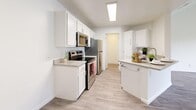 This well-appointed 2-bedroom, 2-bathroom residence in Sandy, Utah offers a bright and clean aesthetic throughout its single-floor layout. The open kitchen and living area form the heart of the home, featuring a galley-style kitchen equipped with stainless steel appliances — including a range, over-the-range microwave, refrigerator, and dishwasher — complemented by crisp white cabinetry, light countertops, and wood-look flooring that extends throughout the space. The living room benefits from vaulted ceilings and a large sliding glass door that floods the room with natural light and provides views of surrounding greenery. Both bedrooms are generously sized, with the primary bedroom offering access to a dedicated closet. The bedrooms maintain the same light flooring and neutral palette, creating a calm and versatile environment. Each of the two bathrooms features a tub-shower combination, white vanity cabinetry, and matching light flooring. A dedicated laundry area houses a full-size washer and dryer. The consistent use of soft whites, light wood tones, and clean finishes throughout gives the residence a cohesive, modern feel that is both functional and inviting.