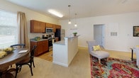 Located at 1100 Deer Harbor Dr in Garner, NC, this single-floor residence offers a thoughtfully designed layout with an open-concept living and kitchen area at its heart. The kitchen is well-equipped with warm wood cabinetry, granite countertops, stainless steel appliances including a refrigerator, microwave, and range, and a central island with bar seating accented by pendant lighting. Light wood-style flooring runs through the kitchen and dining area, while plush carpet extends into the living and bedroom spaces.

The living area flows seamlessly from the kitchen, benefiting from natural light through multiple windows dressed with neutral drapes. Multiple bedrooms are generously sized with plush carpeting and ceiling fans, offering comfortable, well-lit retreats. Each bedroom features ample wall space and natural light from well-positioned windows.

The bathrooms are finished with rich wood vanities, white countertops, and light wood-style flooring. The primary bathroom includes an extended vanity with dual sinks and a shower-tub combination, while the secondary bathroom mirrors the same quality finishes. Neutral wall tones and clean lines throughout the space create a bright, cohesive aesthetic well-suited for everyday living.
