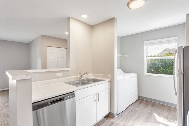 Enjoy modern kitchens featuring a large sink, dishwasher, stainless steel appliances, and bright natural lighting, professionally managed by Highlands Vista Group. - Arbor Crossings