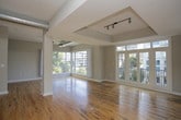 This single-floor urban loft blends industrial character with modern comfort in a thoughtfully designed open-concept layout. Warm, richly toned hardwood floors extend throughout the main living areas, complementing the soaring ceilings and exposed metallic ductwork that give the space its distinctive loft aesthetic. Large windows invite abundant natural light and frame views of the surrounding cityscape and greenery, creating a bright and airy atmosphere.

The expansive living area features a tray ceiling section with a ceiling fan, track lighting, and a striking tile-clad architectural column as a focal point. The kitchen is equipped with dark espresso cabinetry, granite countertops, stainless steel appliances, and a subway tile backsplash, offering both style and functionality. The space flows seamlessly between the kitchen and living zones, ideal for entertaining.

The bedrooms are well-proportioned with large windows offering tree and city views, continuing the hardwood flooring. The bathrooms are finished with slate-style tile floors, granite vanity countertops, white cabinetry, and over-toilet storage. The primary bathroom includes a walk-in closet with built-in shelving, adding a practical and organized storage solution. Throughout, the neutral warm-gray color palette ties all spaces together cohesively.