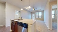 This single-floor, 3-bedroom, 2-bathroom residence offers a thoughtfully designed layout that maximizes functionality and comfort. The open-concept kitchen and living area serves as the heart of the home, featuring a central island with granite countertops, an undermount sink, and elegant pendant lighting overhead. Rich dark-wood cabinetry pairs with a full suite of stainless steel appliances, including a refrigerator, range, microwave, and dishwasher, all set atop durable hardwood-style flooring. The adjoining living room is highlighted by a tray ceiling with a ceiling fan, soft carpeting, and a large window with exterior door access, filling the space with natural light and outdoor views. Each of the three bedrooms offers plush carpet flooring and includes a closet, with the primary bedroom providing generous dimensions. The two bathrooms are well-finished; one features a soaking tub with diagonal-set tile surround accented by a decorative mosaic border, while the other includes a rich wood vanity with granite countertop and hardwood-style tile flooring. A hallway and dedicated closet round out the layout, providing practical storage throughout. The consistent use of neutral tones, quality finishes, and ceiling fans throughout creates a cohesive and comfortable living environment.