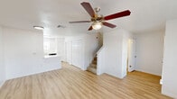 Located at 9888 United Dr in Houston, TX, this two-story home offers four bedrooms and four bathrooms across a generously sized layout. The main floor commands the majority of the living space, while the upper level provides a more intimate secondary area connected by a staircase.

The kitchen is outfitted with crisp white cabinetry, quartz-style countertops, black appliances including a refrigerator and electric range, and a stainless steel sink. Light wood-look flooring runs consistently throughout the home, lending a clean, cohesive aesthetic. An open kitchen and living room area on the main floor creates a natural flow for daily living and entertaining.

Each of the four bedrooms features light-toned hardwood-style flooring, white walls, and ceiling fans with lighting. Windows with blinds allow natural light to filter in while providing views of the surrounding greenery. The bathrooms are finished in a clean, minimalist style with white fixtures, quartz countertops, and combination tub-shower units with ample storage.

A hallway connects the main living areas, and the home's overall palette — bright whites and warm wood tones — creates a fresh, inviting atmosphere. The property also features a spacious grassy yard, offering meaningful outdoor space in this established Houston neighborhood.