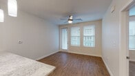 This single-floor unit features a thoughtfully designed open-concept layout connecting the kitchen and living areas. The kitchen is well-appointed with gray shaker-style cabinetry, granite countertops, and a full suite of stainless steel appliances, including a refrigerator, electric range, microwave, and dishwasher. A peninsula with pendant lighting and a built-in sink serves as both a functional workspace and a natural divider between the kitchen and living area. Track lighting and recessed fixtures provide ample illumination throughout the kitchen.

The living and dining area features warm hardwood-style flooring, neutral gray walls, and a ceiling fan with integrated lighting. A glass-paneled door alongside two windows with blinds allows natural light to fill the space. The bedroom is carpeted for comfort, offering its own ceiling fan, two windows with blinds, and generous wall space. The bathroom presents a clean, functional design with wood-look flooring, a granite-topped vanity with gray cabinetry, a full-size soaking tub with a shower, and recessed lighting. Throughout the unit, consistent finishes — including white trim, neutral paint tones, and modern hardware — create a cohesive and contemporary aesthetic.