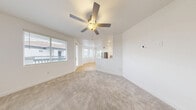 Located at 10115 Jeffreys St in Las Vegas, NV, this 2-bedroom, 2-bathroom residence offers a well-designed single-floor layout with a bright, open feel throughout. The combined living, dining, and kitchen area forms the heart of the home, bathed in natural light from large windows. The kitchen is outfitted with stainless steel appliances — including a French door refrigerator, gas range, and microwave — white shaker cabinetry, a gray subway tile backsplash, and light hardwood-style flooring that extends throughout the cooking and dining spaces. A ceiling fan with integrated lighting anchors the living room, which features plush neutral carpeting and access to a private balcony. Both bedrooms are carpeted and include ceiling fans and windows that bring in natural light; the primary bedroom offers a comfortable, well-proportioned layout. Each of the two bathrooms is finished in clean, crisp white tones with a tub/shower combo, modern fixtures, and light wood-style flooring. Additional conveniences include two closets, a dedicated laundry area, and a hallway connecting the spaces. The overall aesthetic is clean and contemporary with a neutral palette throughout.