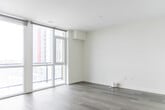Located at 388 King St E in Kitchener, Ontario, this thoughtfully designed unit offers a compact yet efficient single-floor layout. The interior is finished in a clean, modern aesthetic throughout, featuring light grey hardwood-style flooring and crisp white walls that create a bright, airy atmosphere.

An entry hallway welcomes you into the space, leading toward an open-concept kitchen and living area. The kitchen is well-appointed with white cabinetry, stainless steel appliances including a stove and microwave, and dark countertops — all arranged in a galley-style configuration. Floor-to-ceiling windows at the end of the living area flood the space with natural light and provide views to an outdoor balcony, enhancing the sense of openness.

The living area is a clean, versatile space with light-toned flooring and neutral walls, offering a blank canvas for personalization. A secondary room, visible from the living space, opens directly to one of the two bathrooms, which features a vanity with cabinetry and a mirror.

The two bathrooms are finished to a contemporary standard. One includes a soaking tub surrounded by large-format grey marble-effect wall tiles and chrome fixtures, adding a touch of elegance. The second bathroom is clean and functional with a minimalist design.

Overall, the space presents a modern, move-in-ready environment well-suited for urban living in downtown Kitchener.